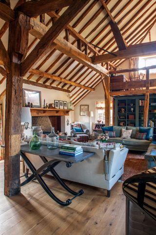 living room with oak framed beams, two sofas and glass table with books