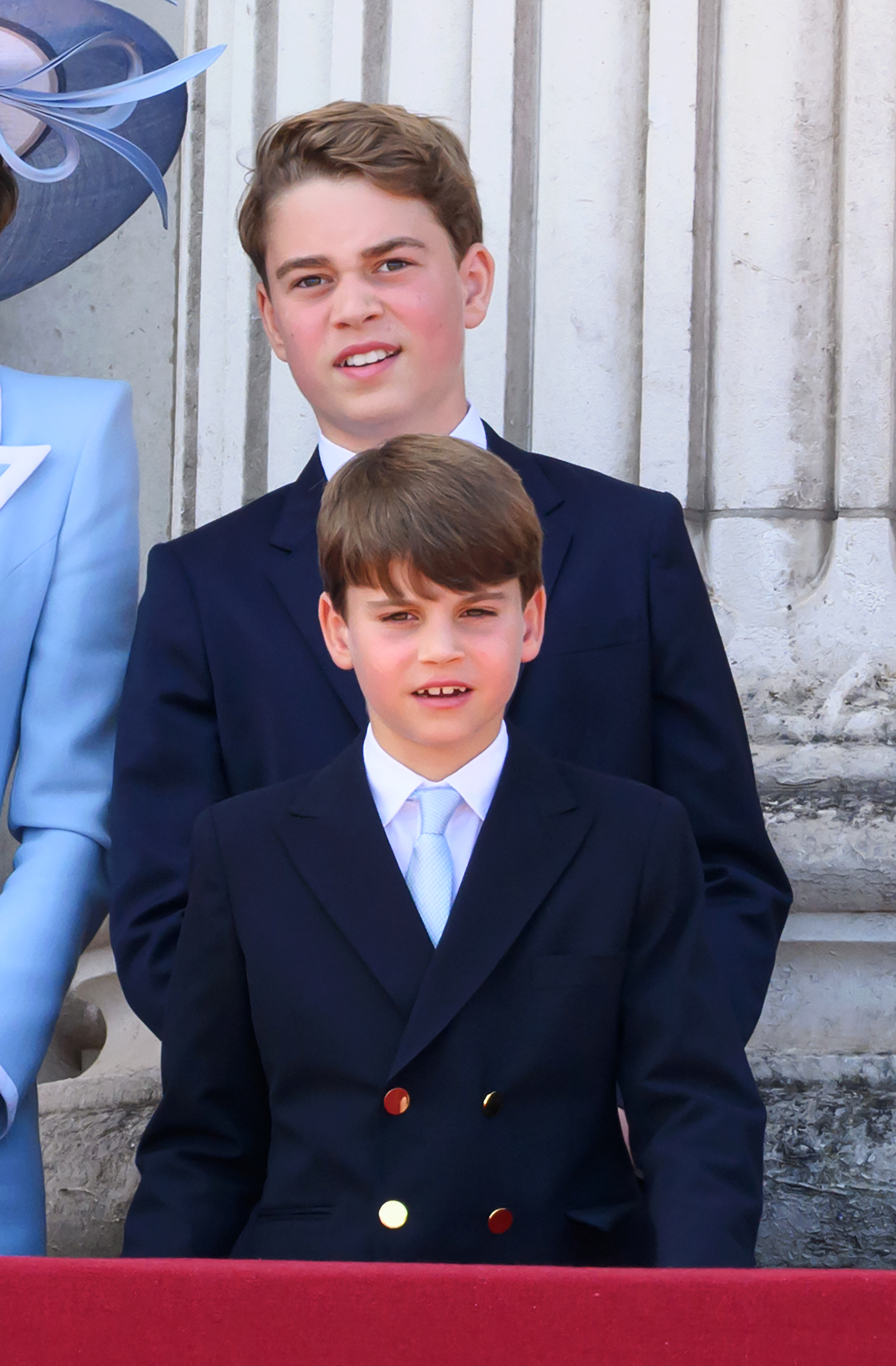 Prince Louis wears a navy blazer with gold buttons and a white shirt with a baby blue tie, which matched brother Prince George and mom Princess Kate's Trooping the Colour outfits