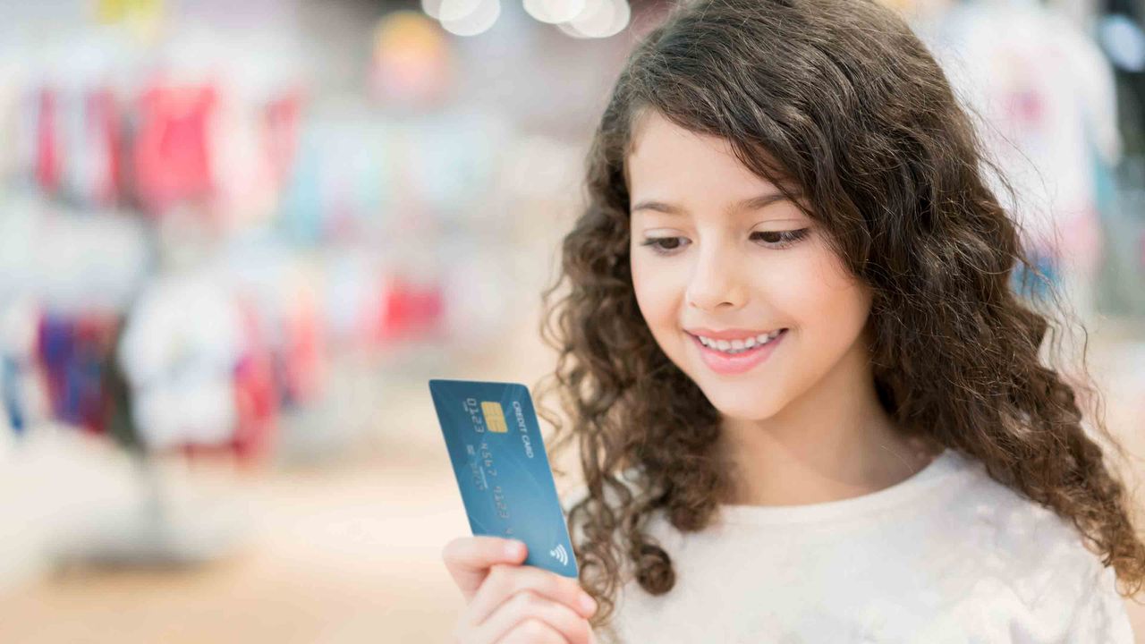 Girl holding parent&amp;#039;s credit card in store