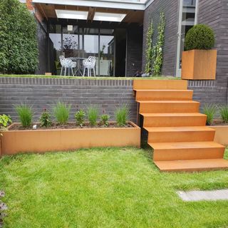 Sloping garden ideas: Corten steel garden steps connecting a patio and lawn area