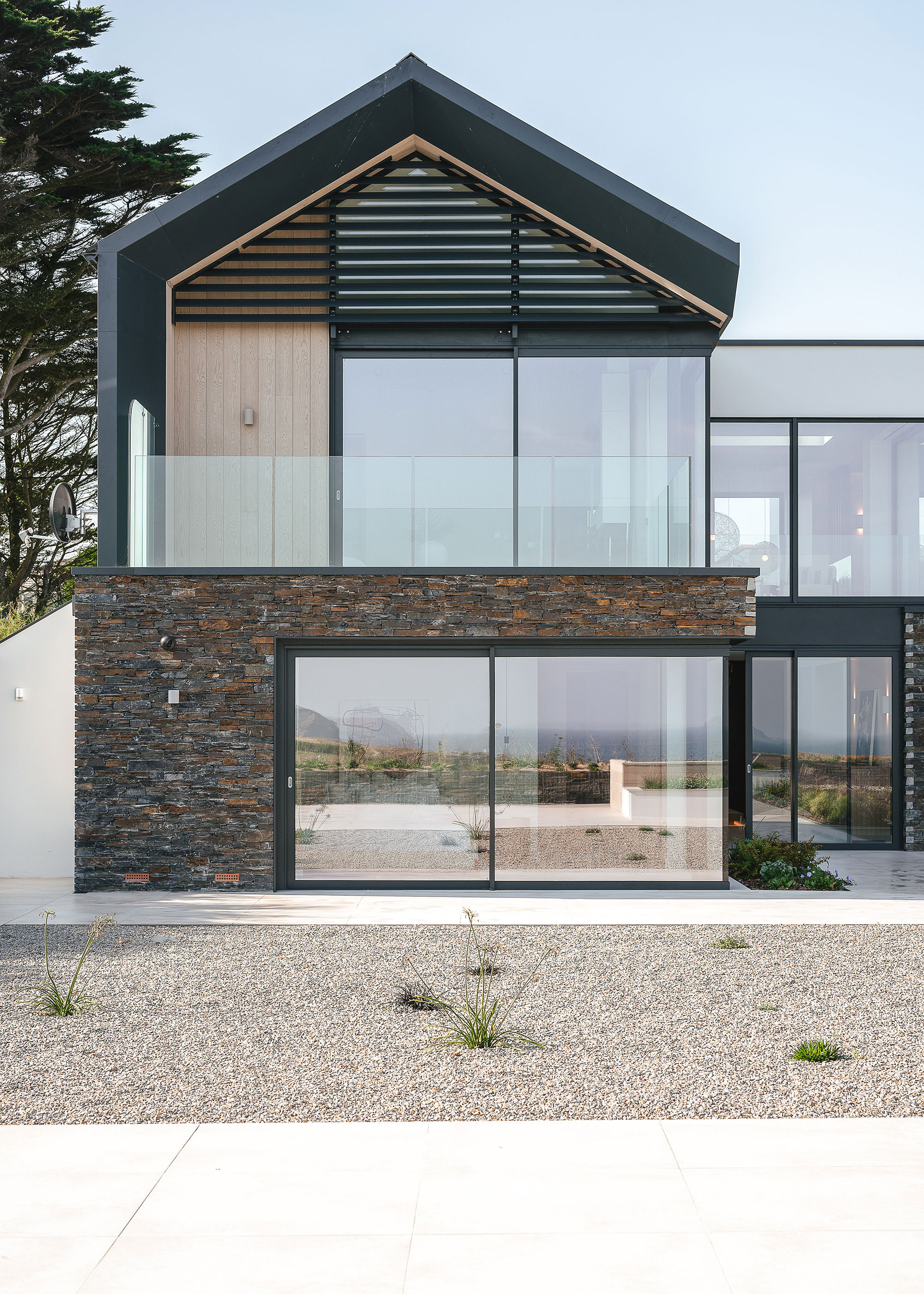 contemporary coastal house with stone cladding and vertical brise soleil and large sliding glazing