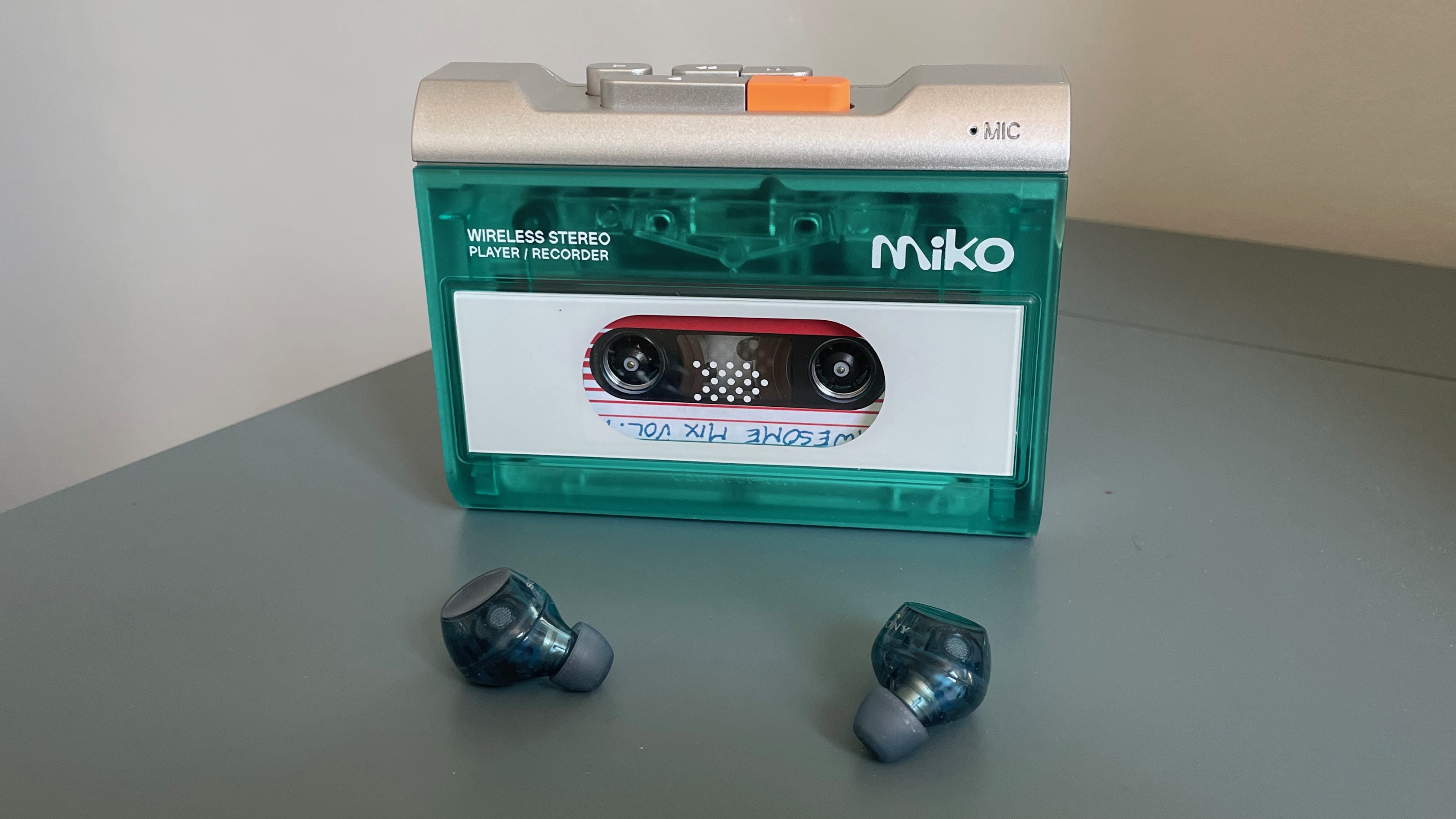 The Gadhouse Miko cassette player on a blue desk with the Sony WF-C710N wireless earbuds in front of it.