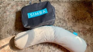 Simba body pillow next to its carrying case