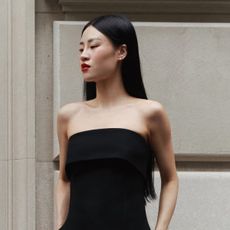 A photo of an Aritzia model wearing a strapless fitted bustier top with black trousers.