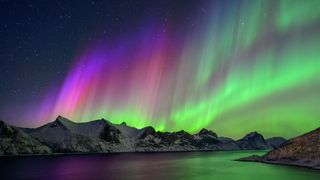 colorful waves of light in the sky above a mountain range