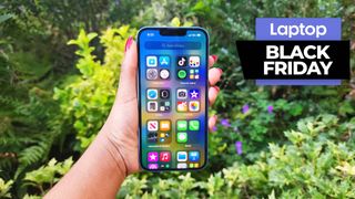 Black Friday iPhone 14 deals — iPhone 14 in hand against a foliage background
