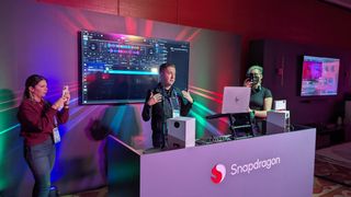 Qualcomm representative presenting DJ booth with Snapdragon X-powered laptop and people taking pictures