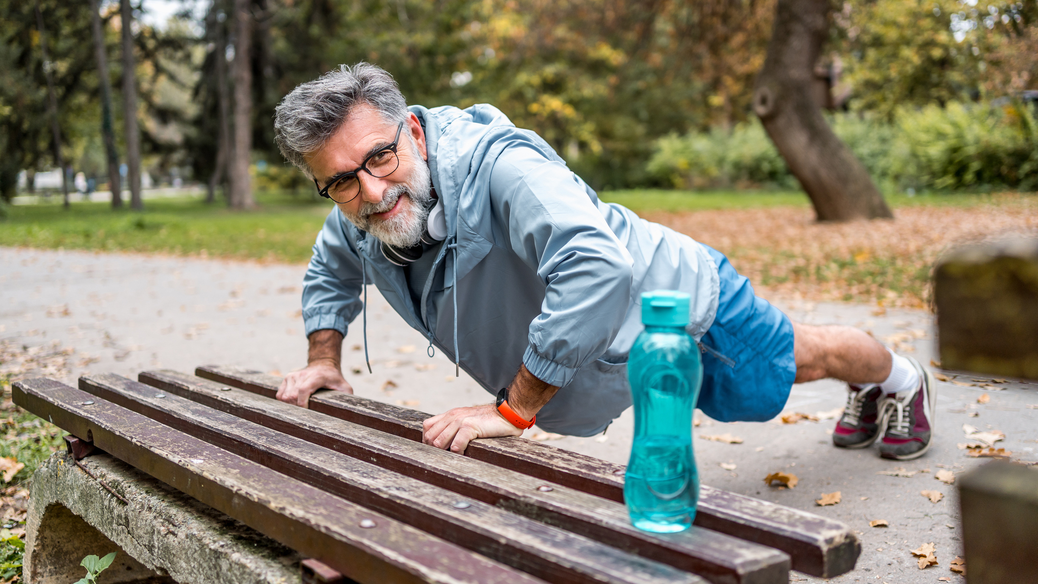 Man performing push-up outdoors with hands resting on a bench