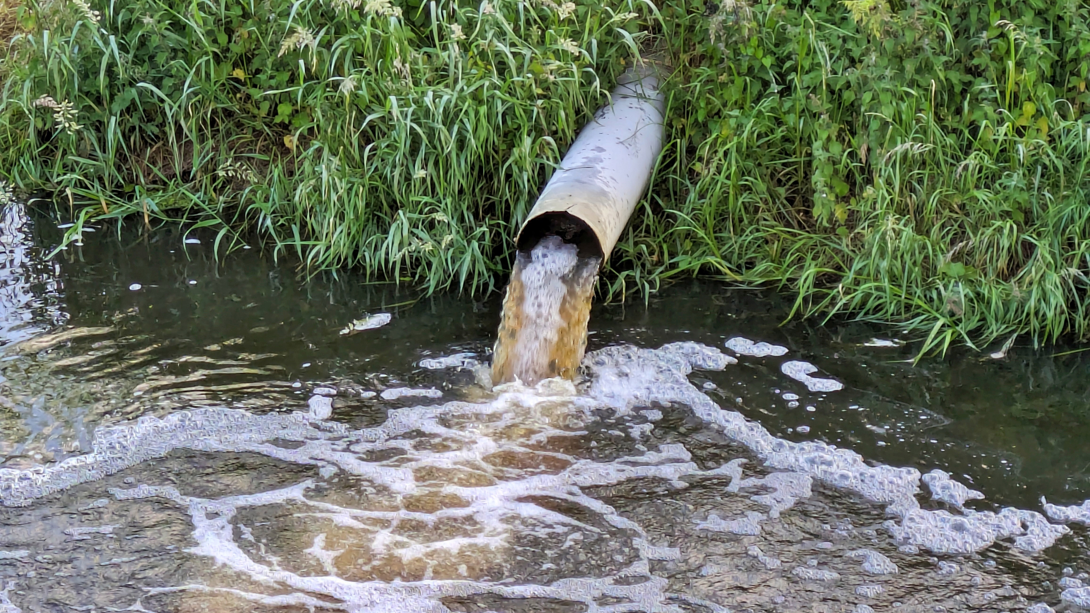 An outflow pipe discharging waste into a river