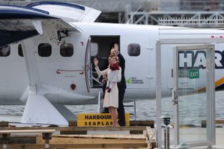 William and Kate waving in front of a seaplane with baby Prince Charlotte and Prince George