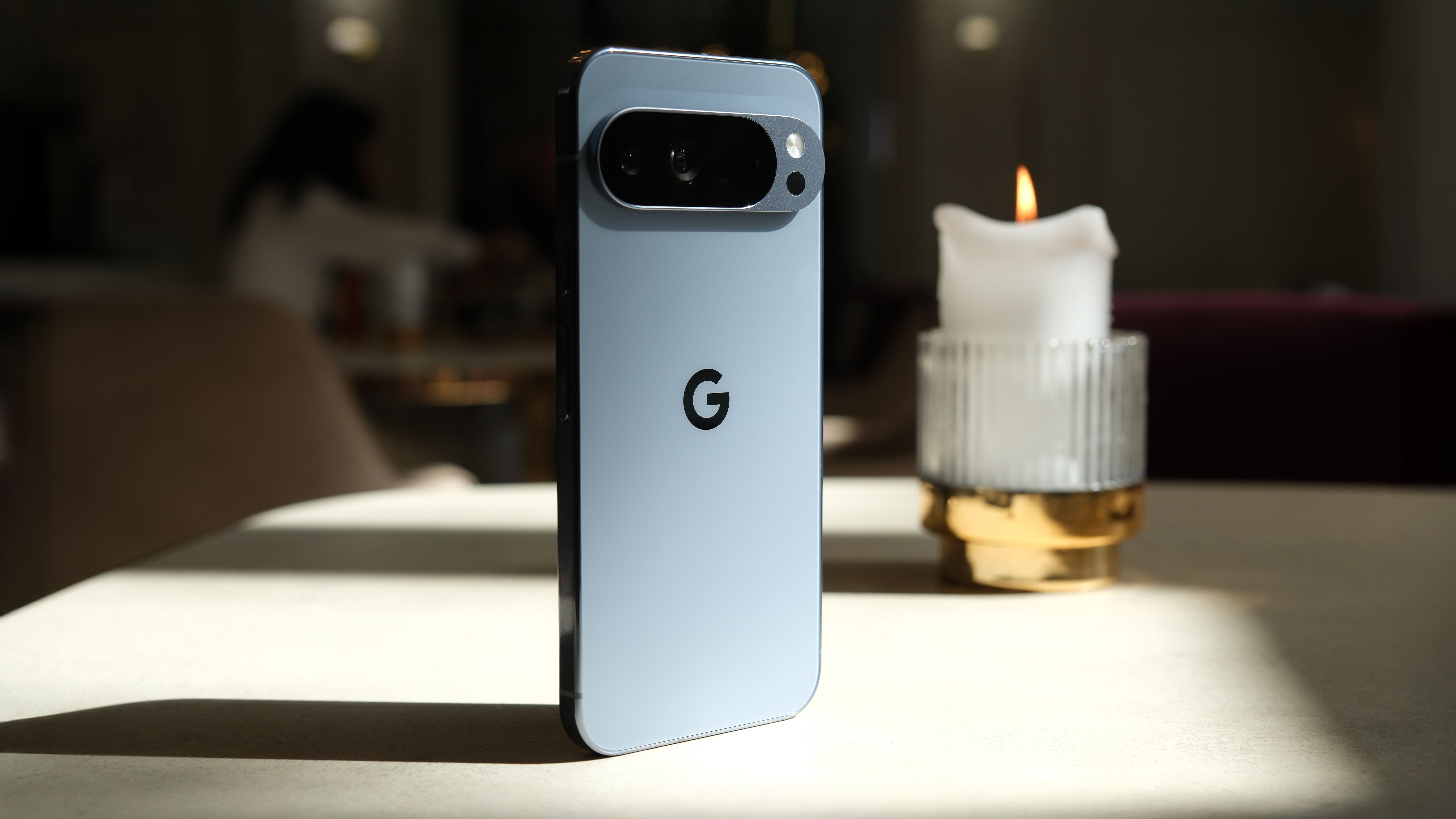 Google Pixel 10 Pro XL on a marble surface in the sun next to a lit candle