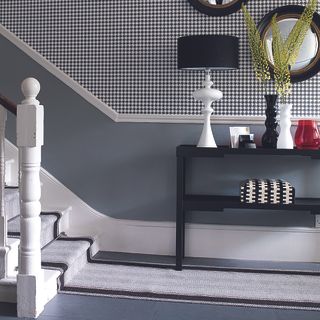 Black and white hallway with black console table and lamp.