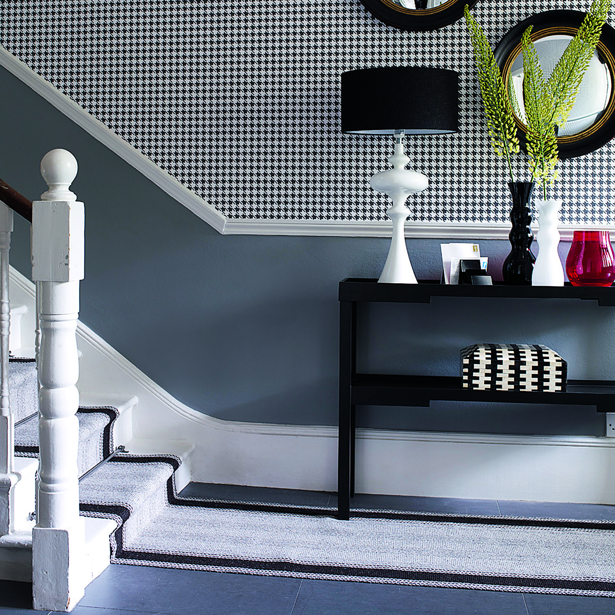 Black and white hallway with black console table and lamp.