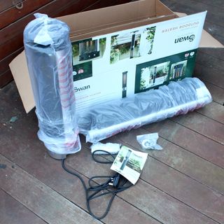 The Swan Column patio heater being unboxed on wooden decking