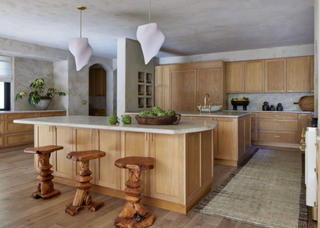 Large wooden traditional kitchen with two kitchen islands. One island has a small, shell shaped sink on it.