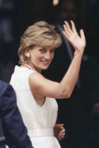 Princess diana wearing a white sleeveless dress turning to the camera and waving in 1996