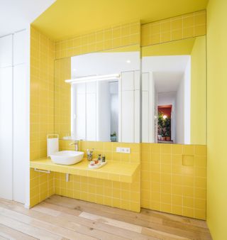 A bathroom with bright yellow tiles and paint