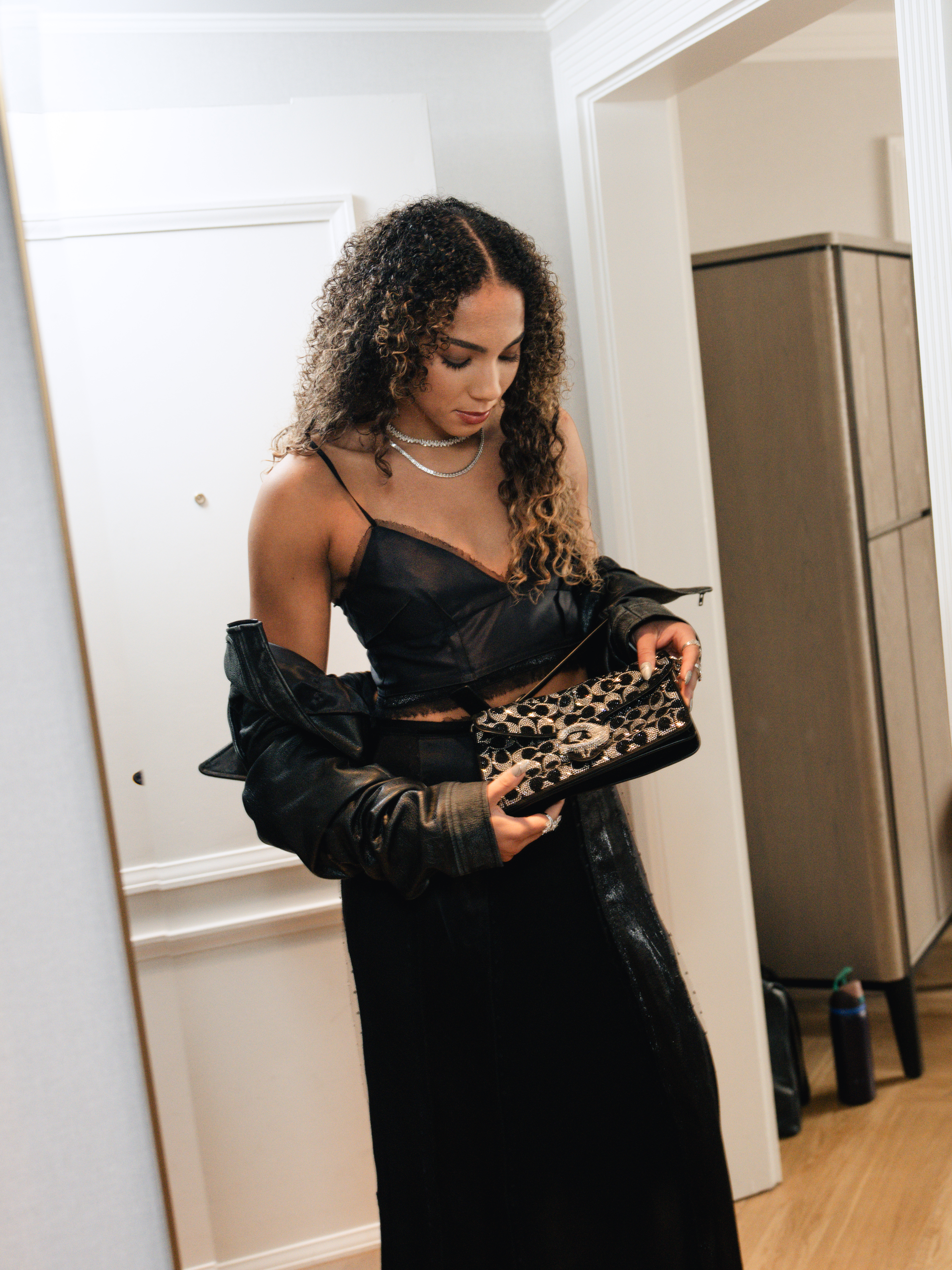 Kiki Rice wearing a custom Coach two-piece set with a leather jacket, platform heels, and a small shoulder bag for the WNBA Draft.