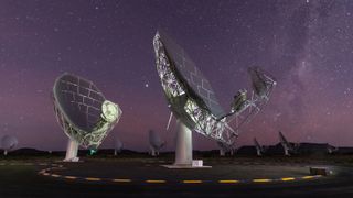A photo of two radio dishes pointed up at the night sky