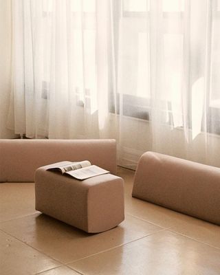 Minimalist seating in a pale pink fabric, with matching table with an open book