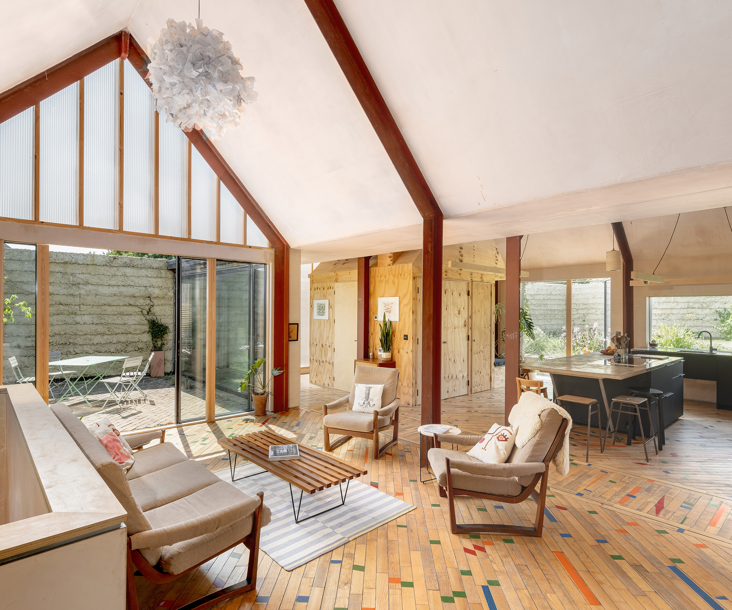 An open plan living room and kitchen in a self build. With exposed beams and pillars and wooden floor