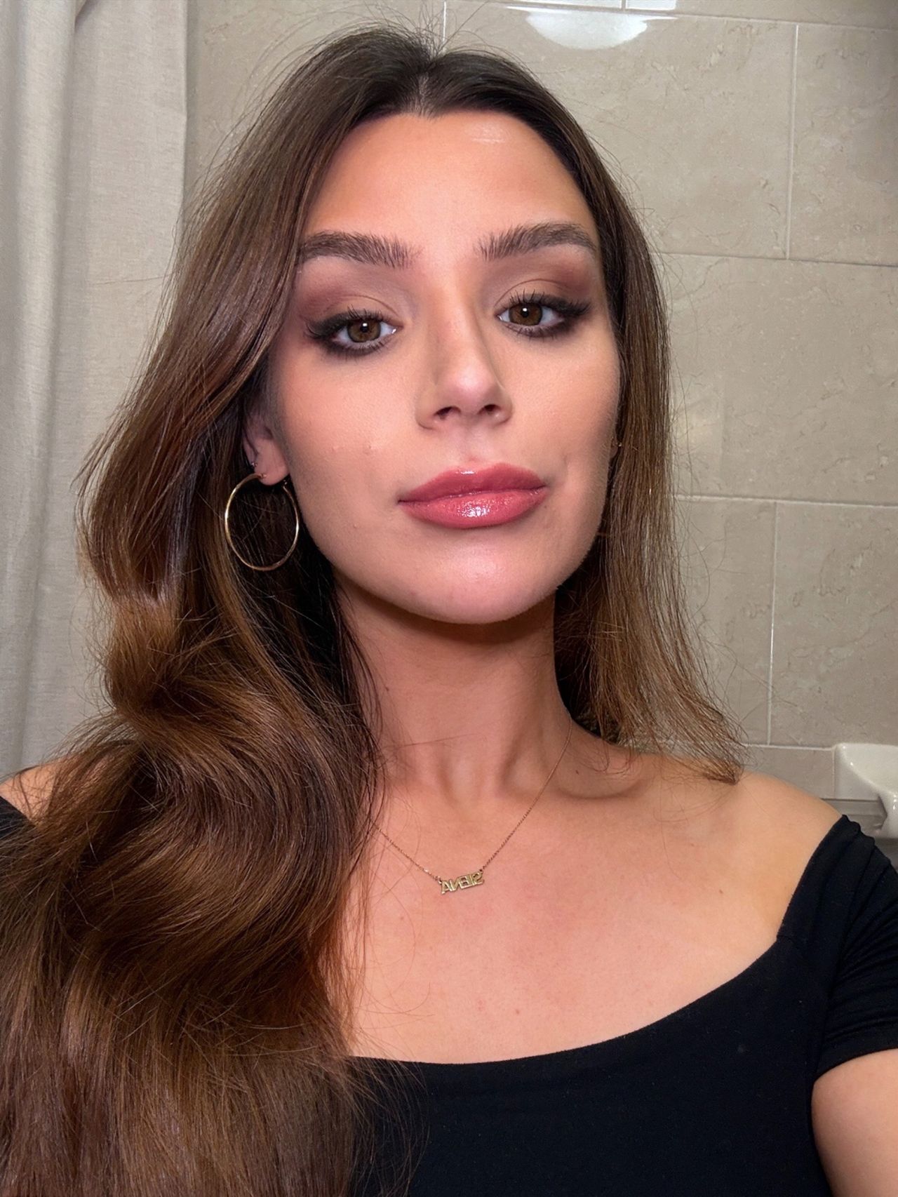 Close-up selfie of me wearing blended contour, soft brown eye makeup, glossy pink lips, gold hoop earrings, and a black off-the-shoulder top.
