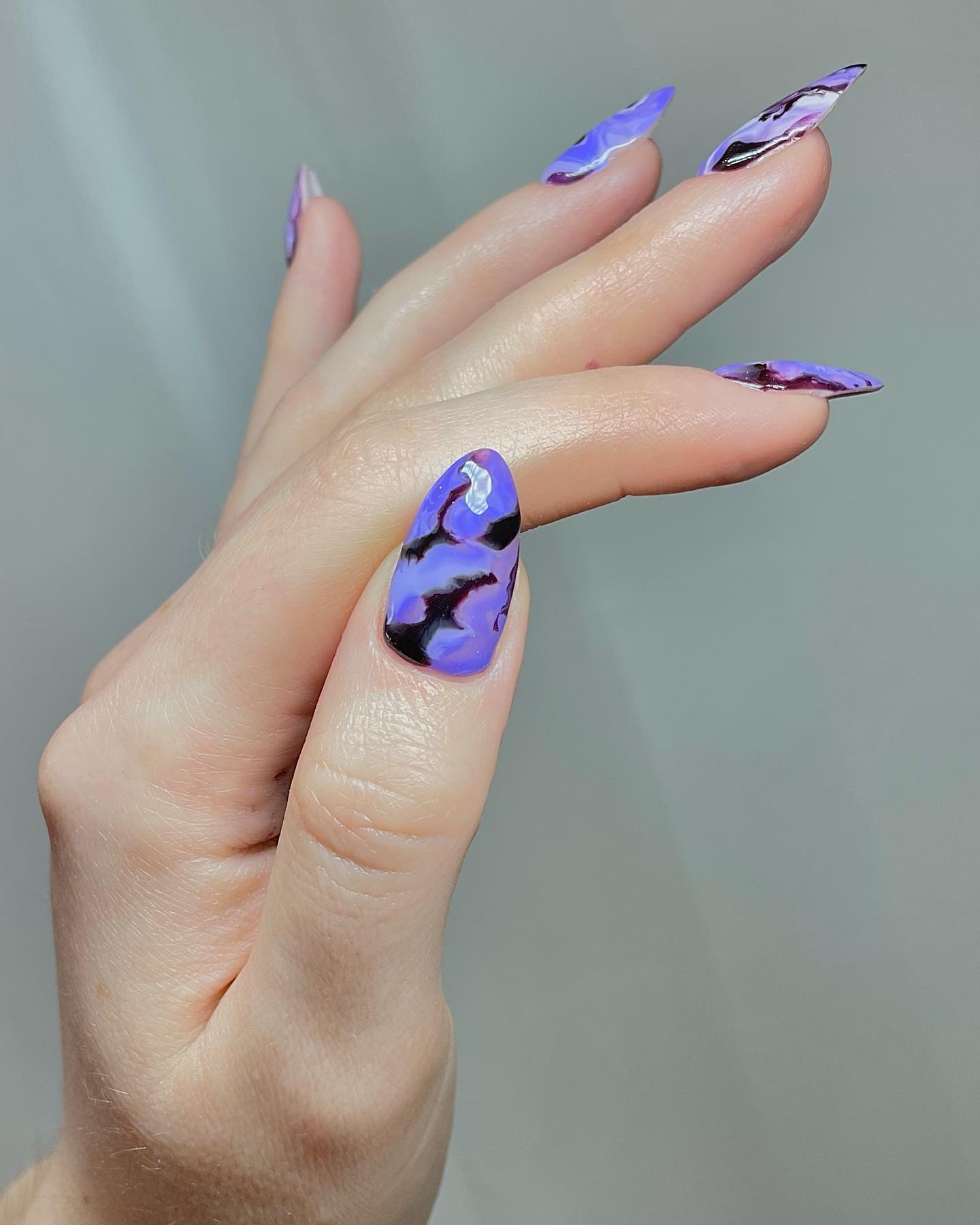 A striking purple and black lighting-esque nail design