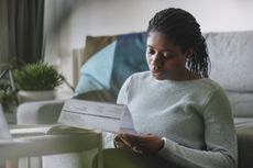 A woman at home reading a utility bill