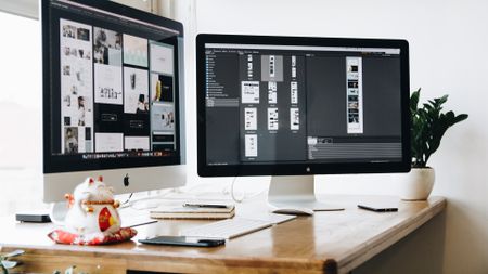 Website being built on Mac, shown across two separate monitors at a desk