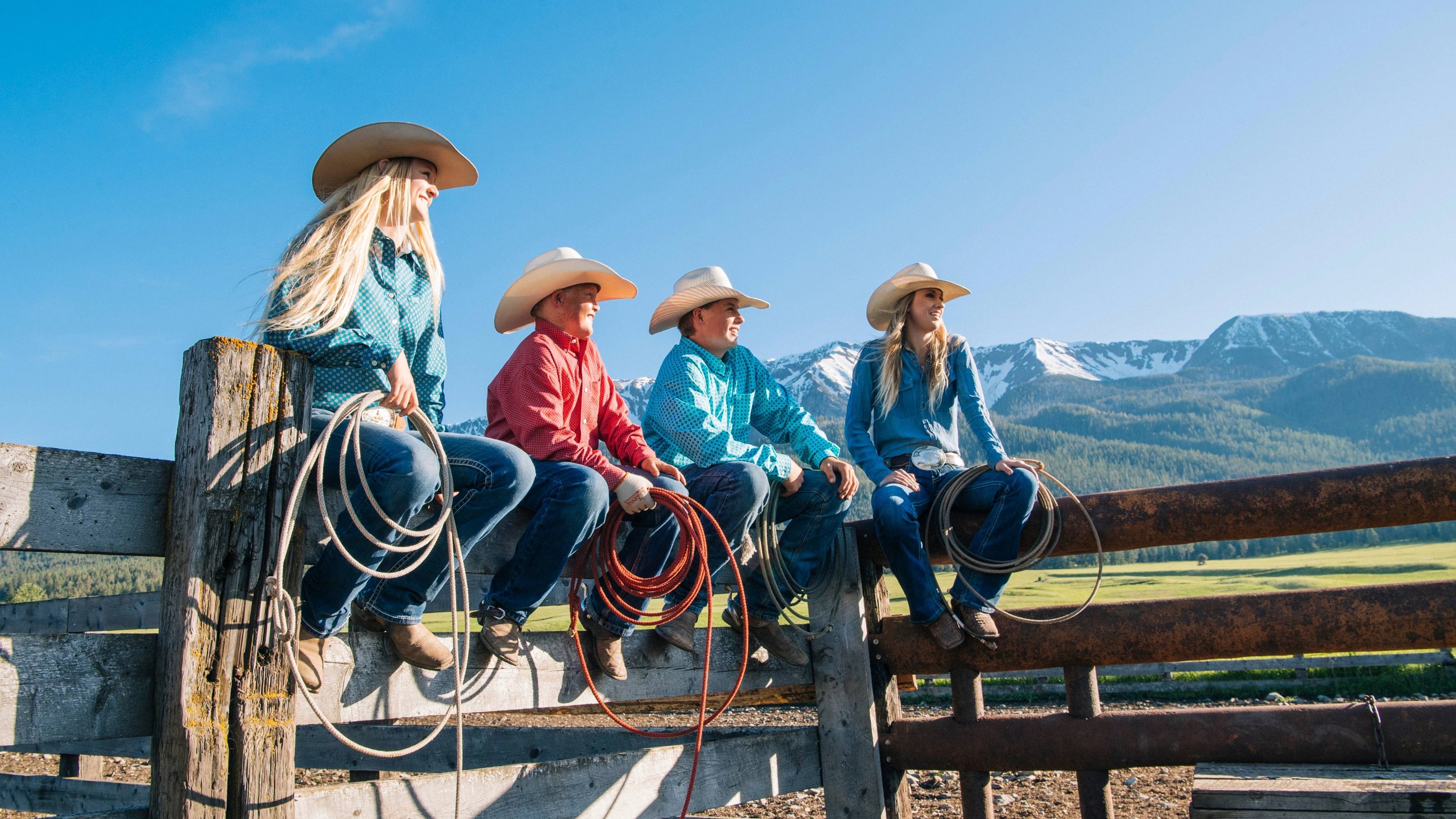 Cowboys and cowgirls on fence, looking away