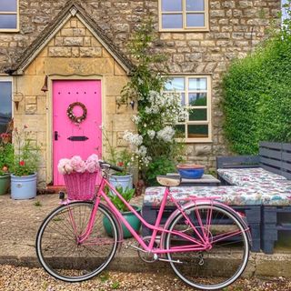 blue pallet furniture in front of a Cotswold cottage with a pink door