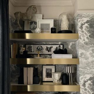 grey designed wall brass shelf with frames and showpieces