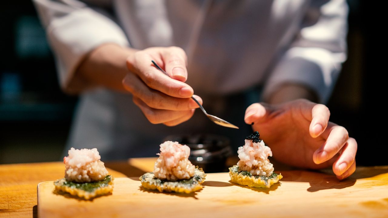 a chef spooning sauce on three small bites