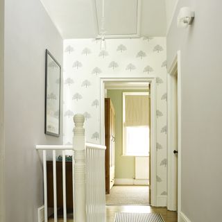 Cream upstairs hallway with carpet runner and wallpaper.