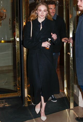 Sophie Turner wearing a black coat