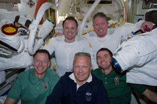 Following the 6 1/2-hour spacewalk of NASA astronauts Ron Garan (top left) and Mike Fossum (top right) on July 12, 2011, five members of the joint shuttle-station crew pose for photographs in the Quest airlock of the International Space Station. Remaining inside but contributing greatly to the outside duo were, from left front, NASA astronauts Chris Ferguson, STS-135 commander, Doug Hurley, pilot, and Rex Walheim, mission specialist. Garan and Fossum are flight engineers for the station's Expedition 28 crew. It was the last spacewalk of NASA's shuttle era and performed during the STS-135 shuttle mission.