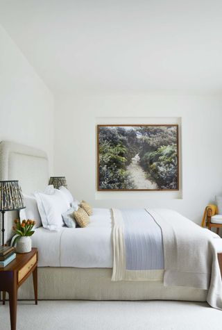 A bedroom that has white linen bedsheets and colored accents