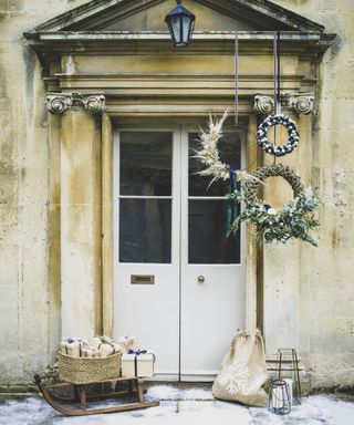 Rustic styled front porch with natural materials, wreaths, vintage sleigh and presents