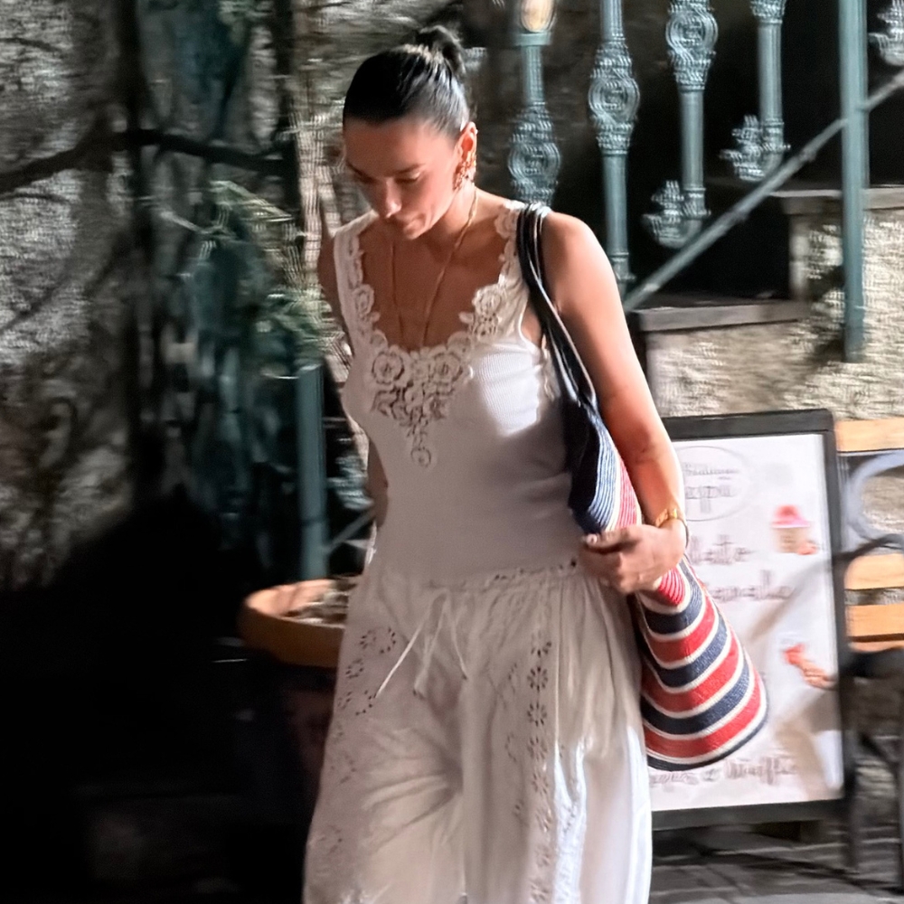 Dua Lipa walks down the street wearing bloomer trousers with a white lace-trim tank top.
