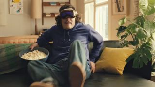 A still from the Apple Vision Pro advert showing someone wearing the device while sitting down with a bowl of popcorn
