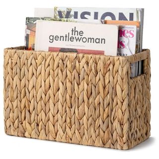 A woven grass magazine holder basket with cut-out handles. 