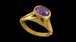 这枚金戒指镶有一颗紫色的半宝石，可能是紫水晶。