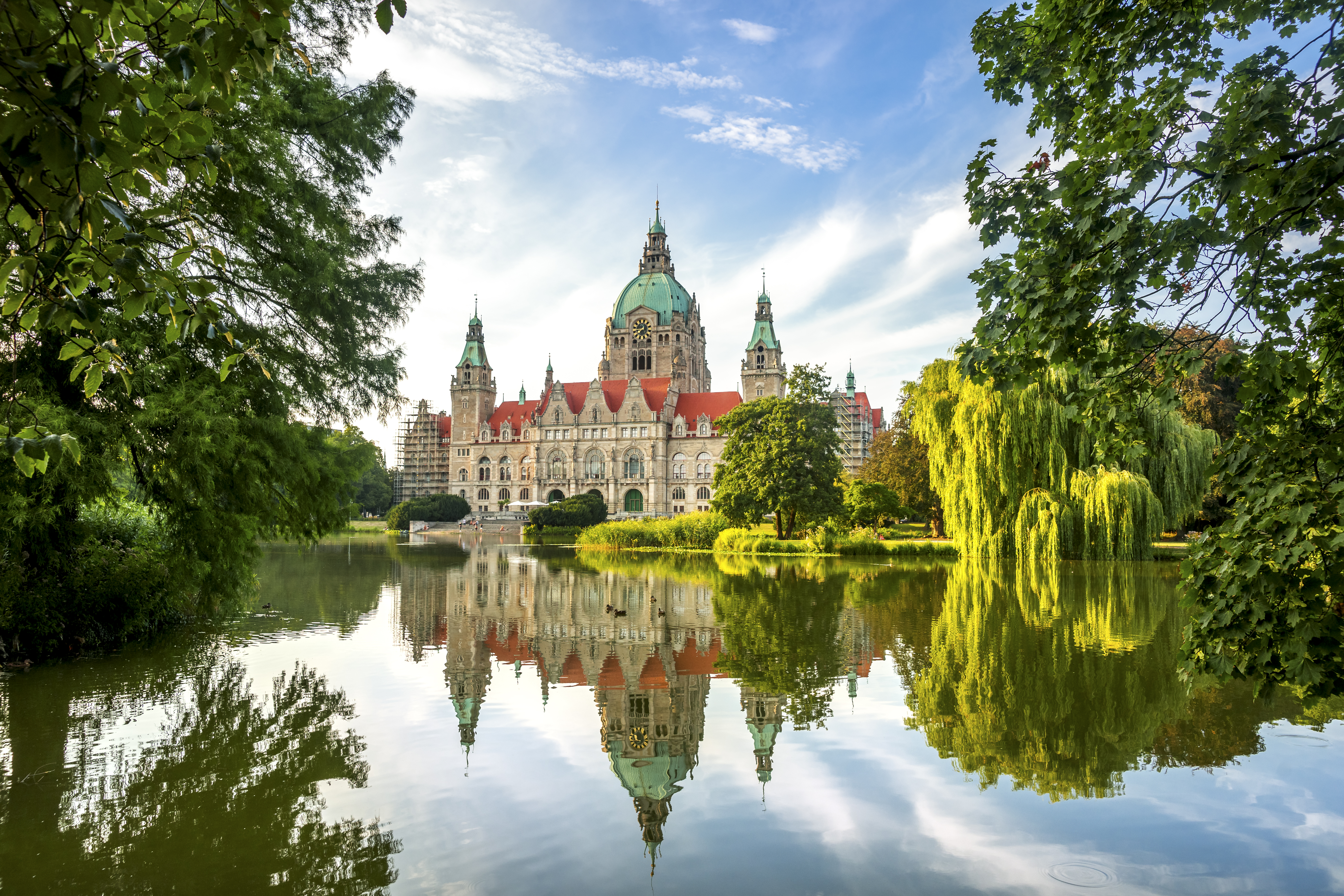 A 20th century grand building with blue copper domed roof on a lake surrounded by trees