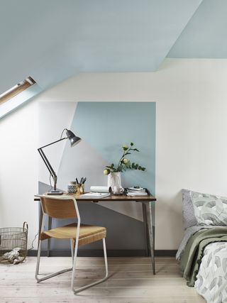 Home office space in a corner of a bedroom with a colourful paint effect behind the desk, and a low bed next to it