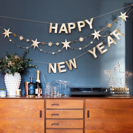 A blue-painted living room decorated with a New Year's Eve bunting, drinks set up on the sideboard and decorated with a star-shaped light