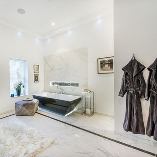 bathroom with white wall and black bath tub