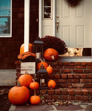 Pumpkins on the steps on a porch with black lanterns