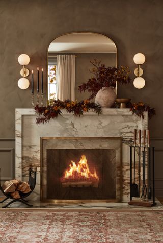 A marble fireplace decorated with a mirror with two lights either side
