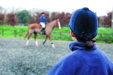 riding lessons , jumping lesson, horse riding lesson in safe arena, instructor looking on as rider moves around arena, riders wearing body protectors