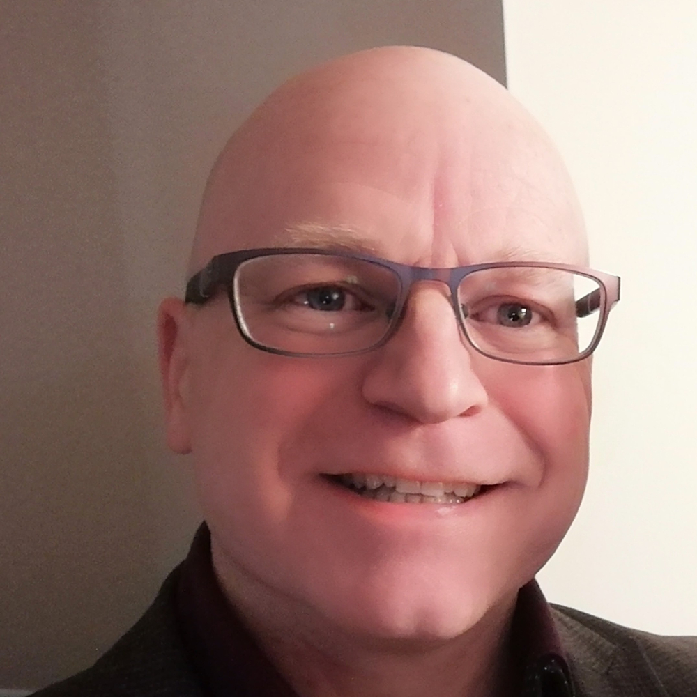 male with no hair and black glasses